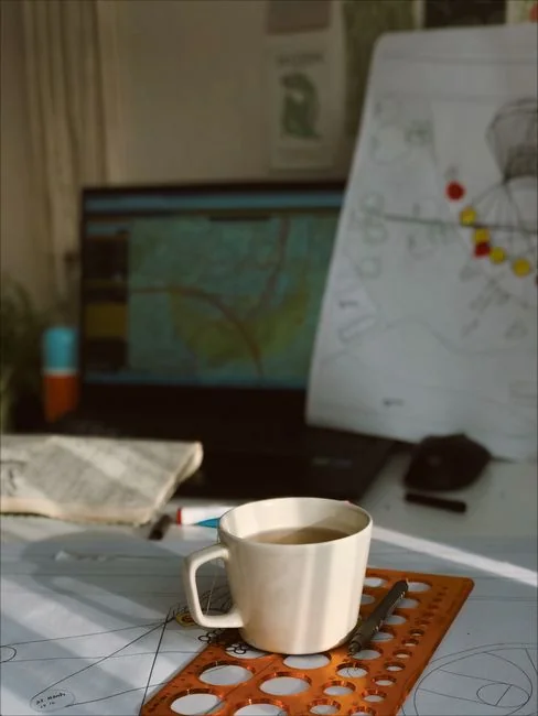 A silhouette of a fashion designer examining a creative mood board filled with fashion sketches and photos.